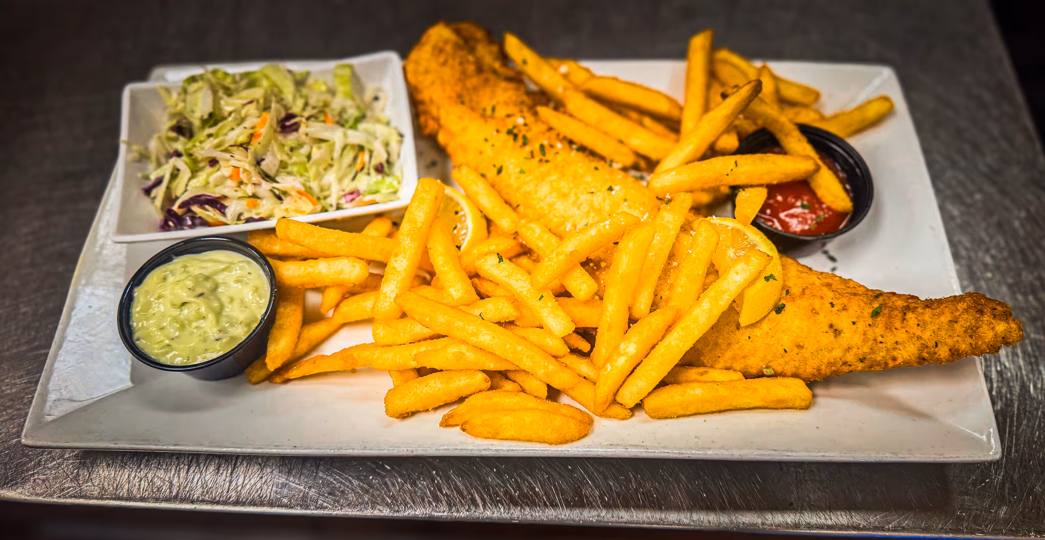 A plate of fries and fish on a table.