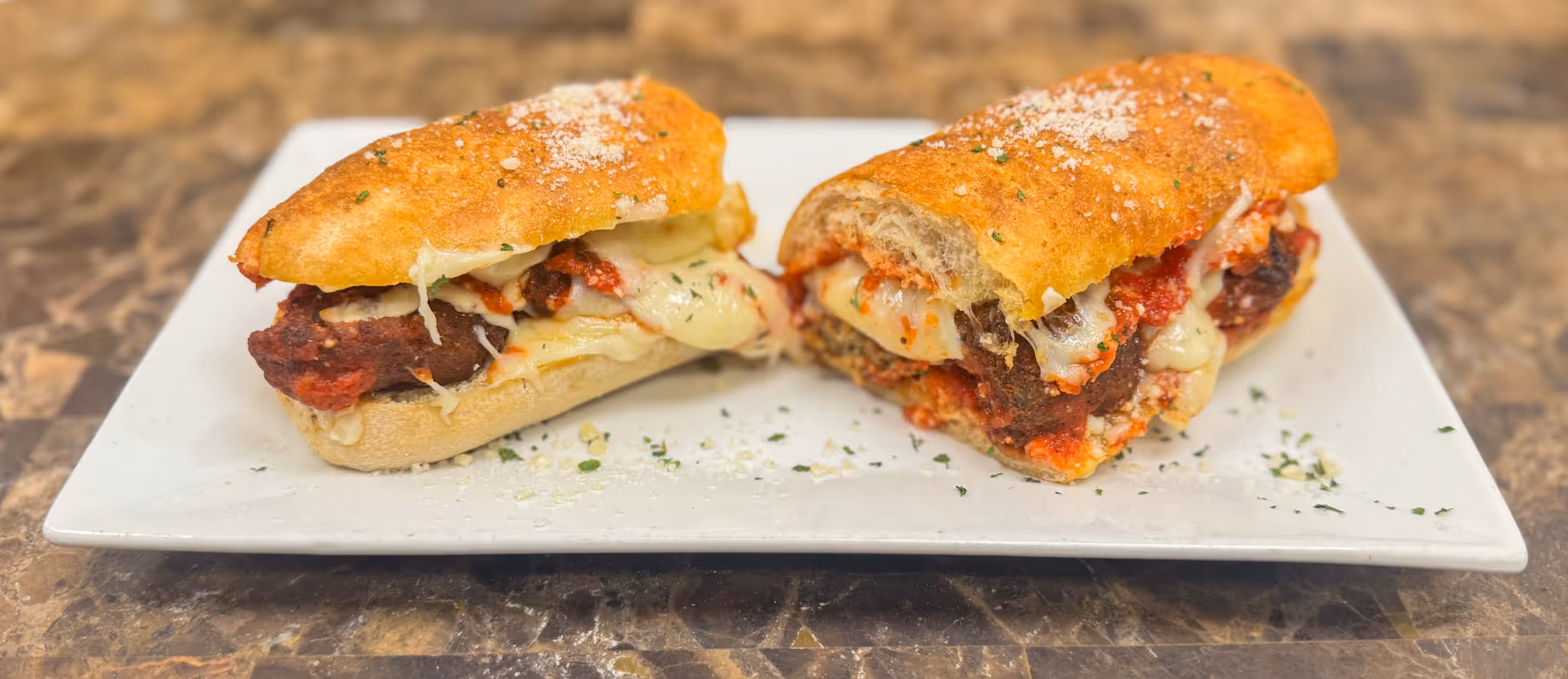 A sandwich with meat and cheese on a white plate.