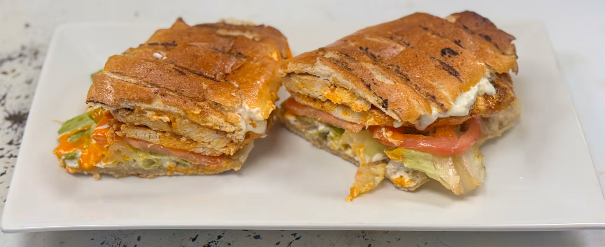 A sandwich cut in half on a white plate.
