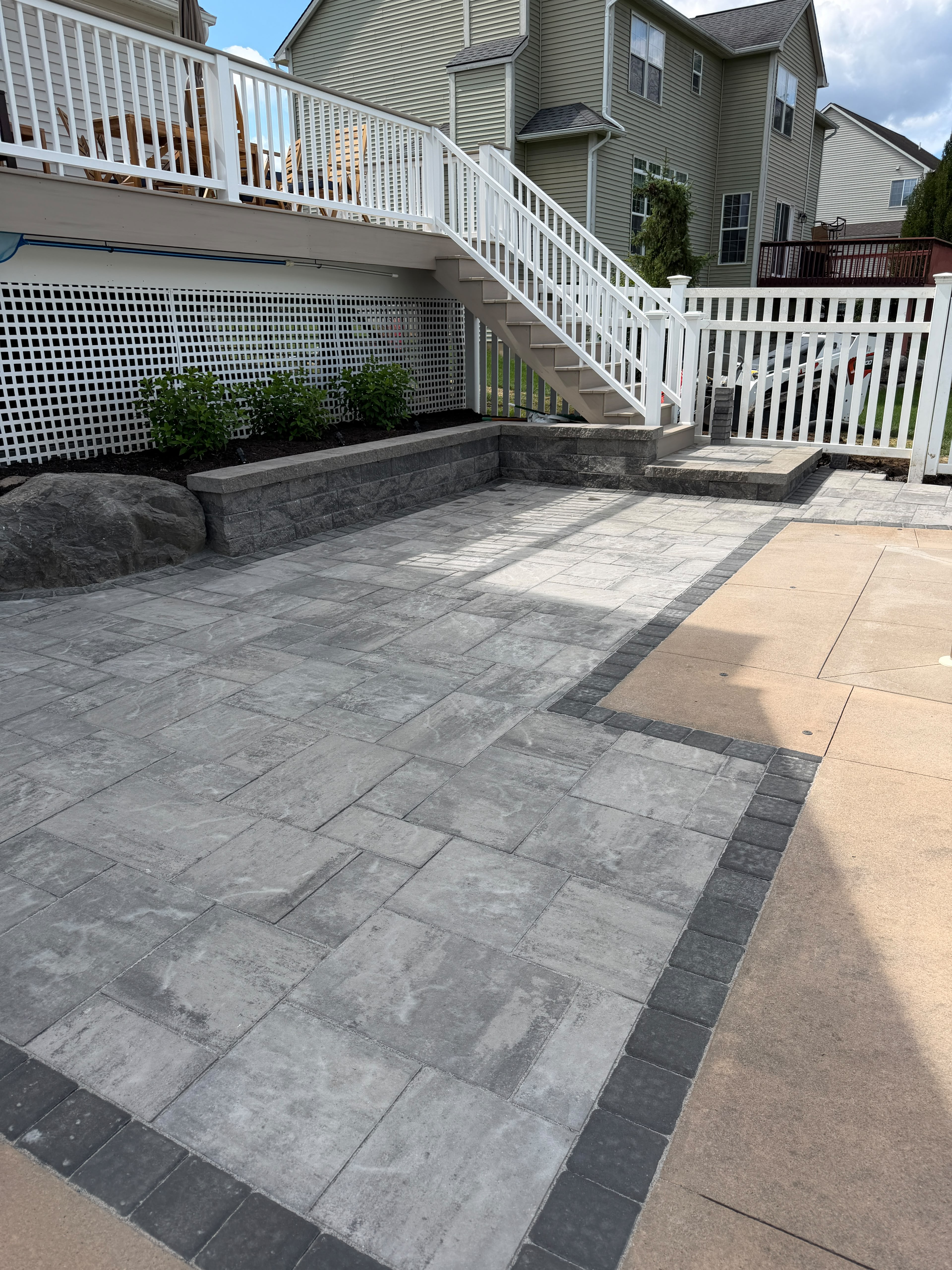 Large-format gray paver patio with charcoal border next to a pool deck