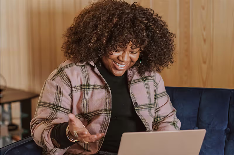 A woman sitting on a couch using a laptop computer.