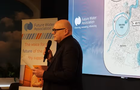 Paul Horton, CEO of Future Water Association, with microphone giving a presentation in front of a screen and a Future Water Association banner.