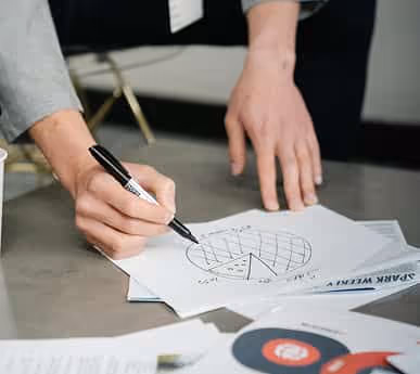 Person drawing and labeling a pie chart on paper with a black marker.
