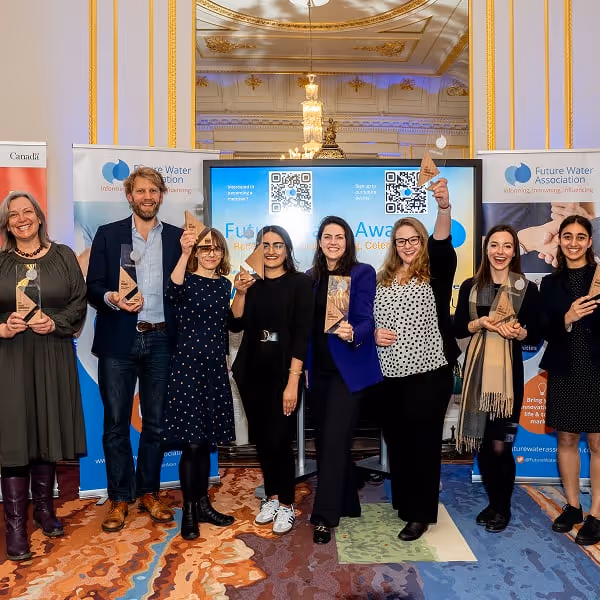 Group of eight people standing indoors holding awards, smiling in front of a screen with Future Water Association banners.