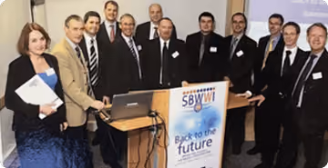 SBWWI team standing around a podium with a sign that reads 'SBWWI Back to the Future.'