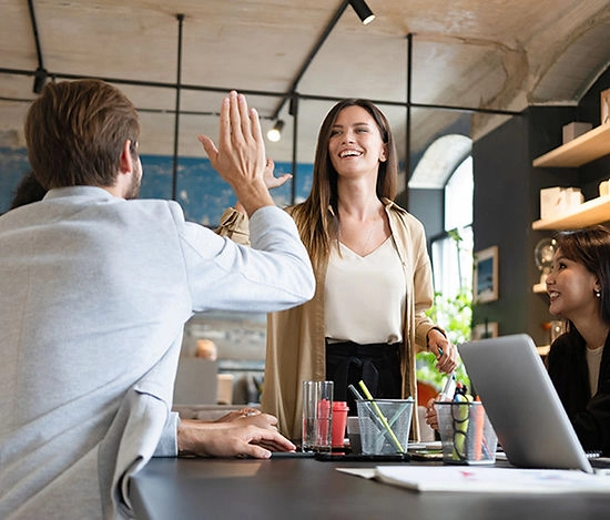A smiling woman in a gray apron processes a payment at a small business counter in a café