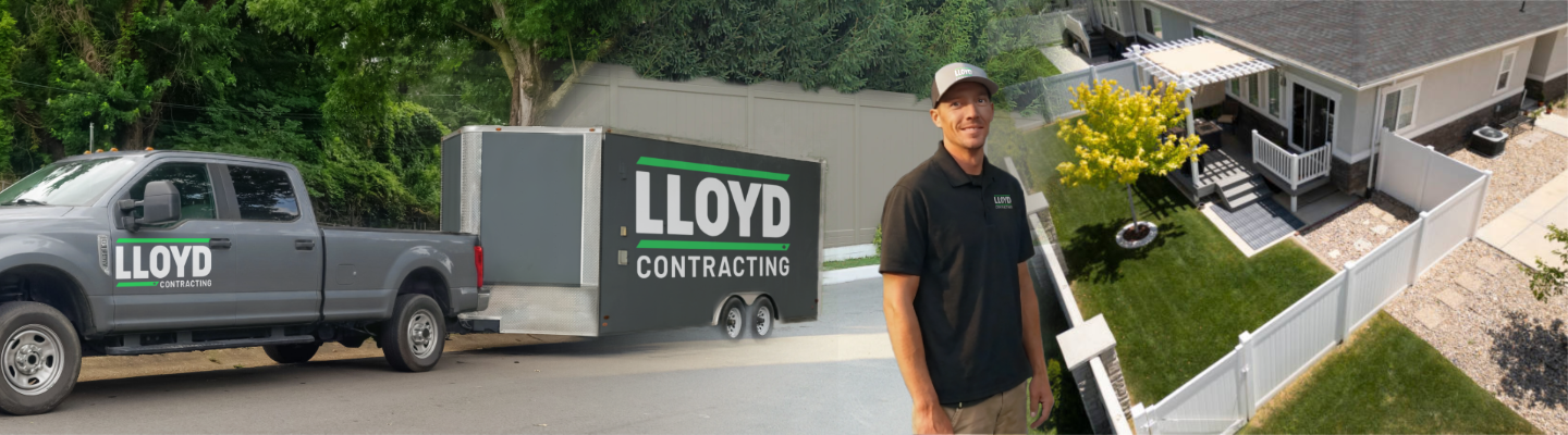 Man in black Lloyd Contracting polo and cap standing beside a truck and trailer with Lloyd Contracting logos, with a house and yard in the background.