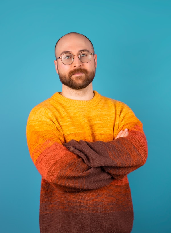 Smiling man wearing a yellow sweater on a solid backdrop