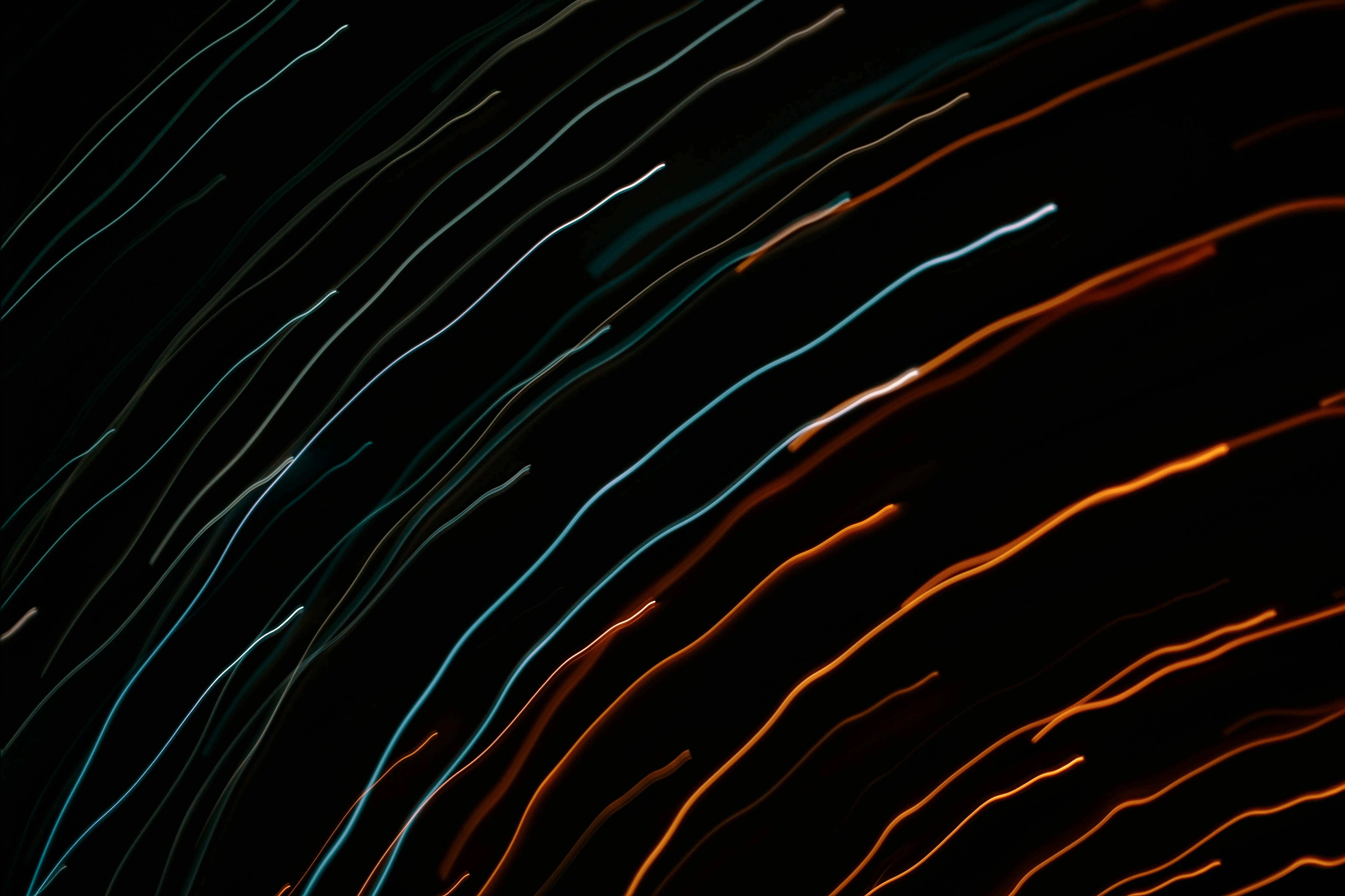 Abstrakte Lichtspuren in Blau- und Orangetönen vor schwarzem Hintergrund.