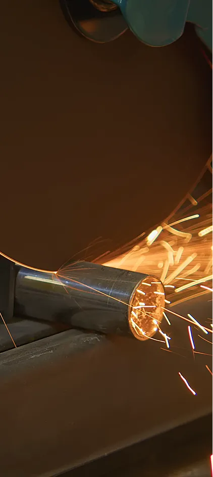 Grinding sparks flying off a metal pipe being cut by an industrial cutting wheel.