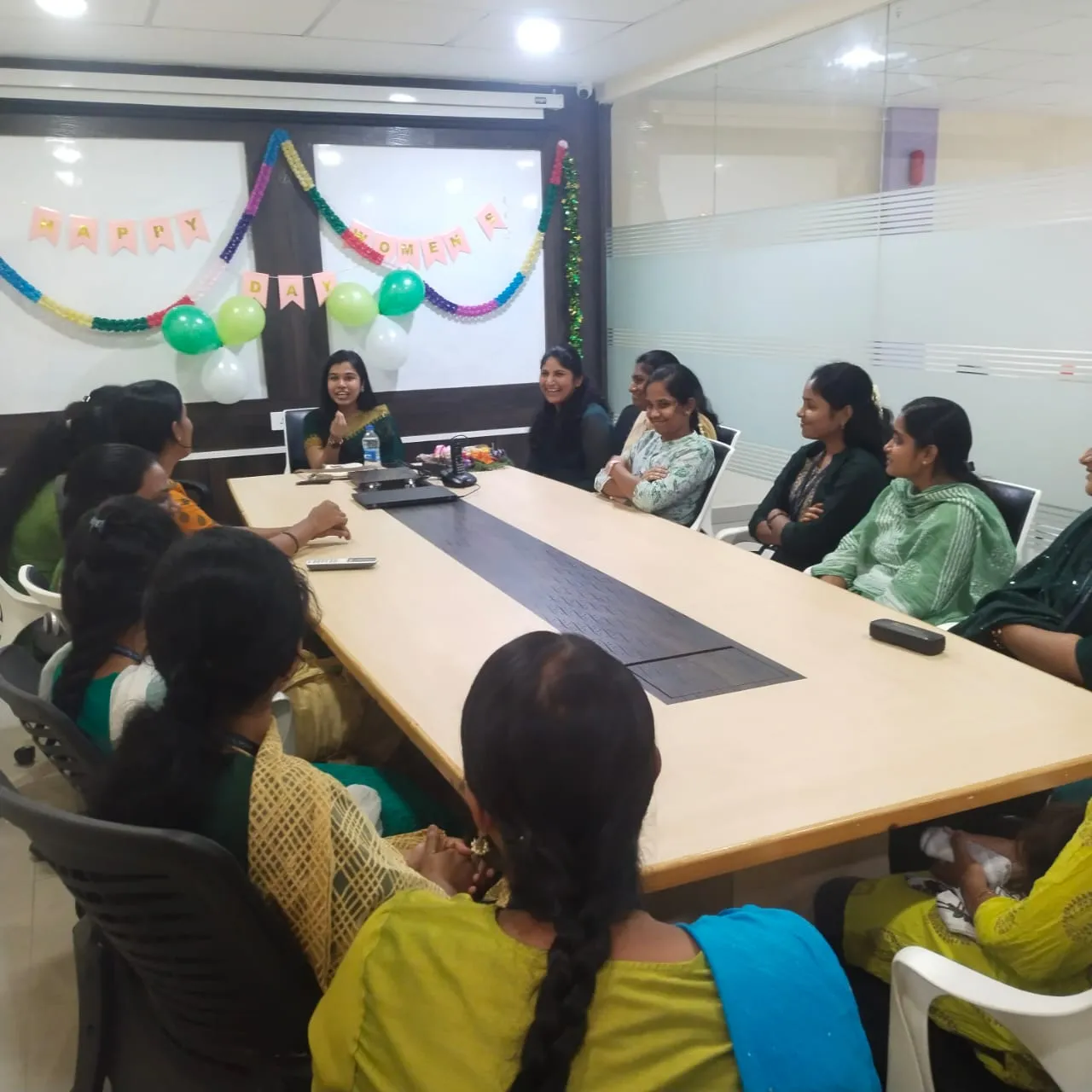 A grayscale photo of a diverse group of four people looking at a laptop screen together.