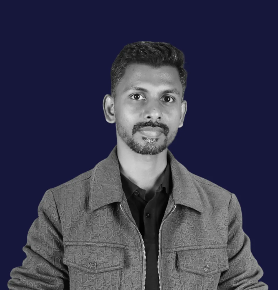 Professional portrait of a male executive sitting at a desk in an office setting.