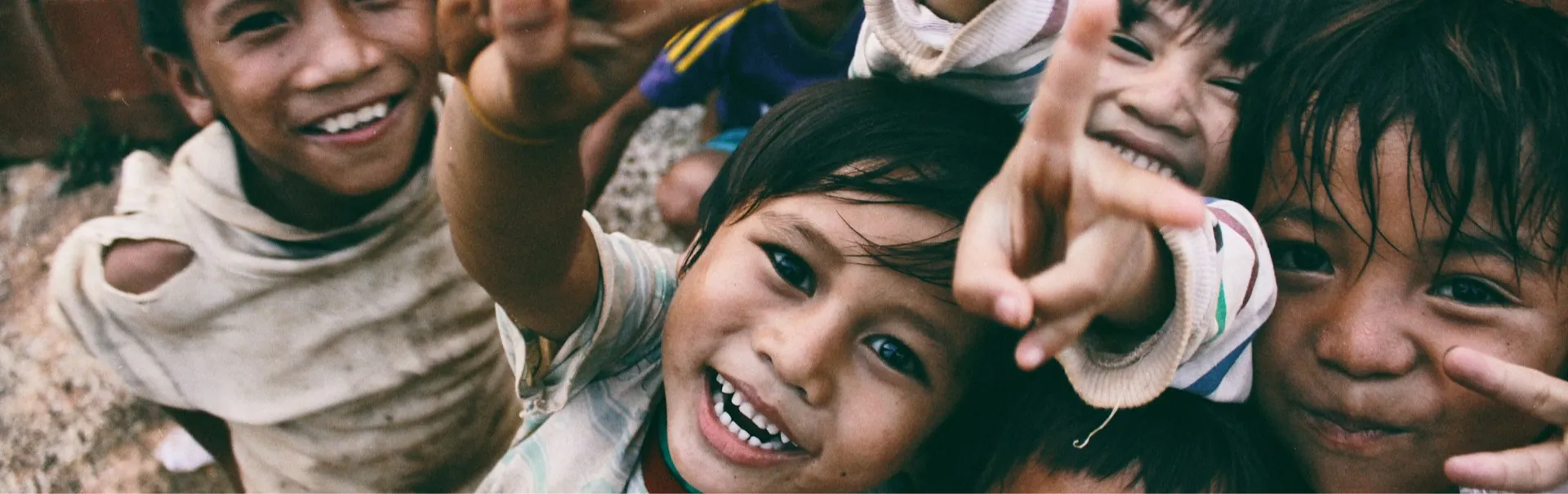 A wide grayscale photograph of smiling children used as the hero background for the community impact section.