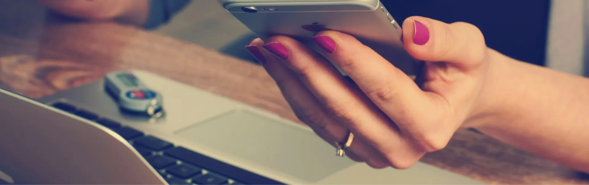 Grayscale image of a person holding a smartphone over a laptop, used for the hero section background.
