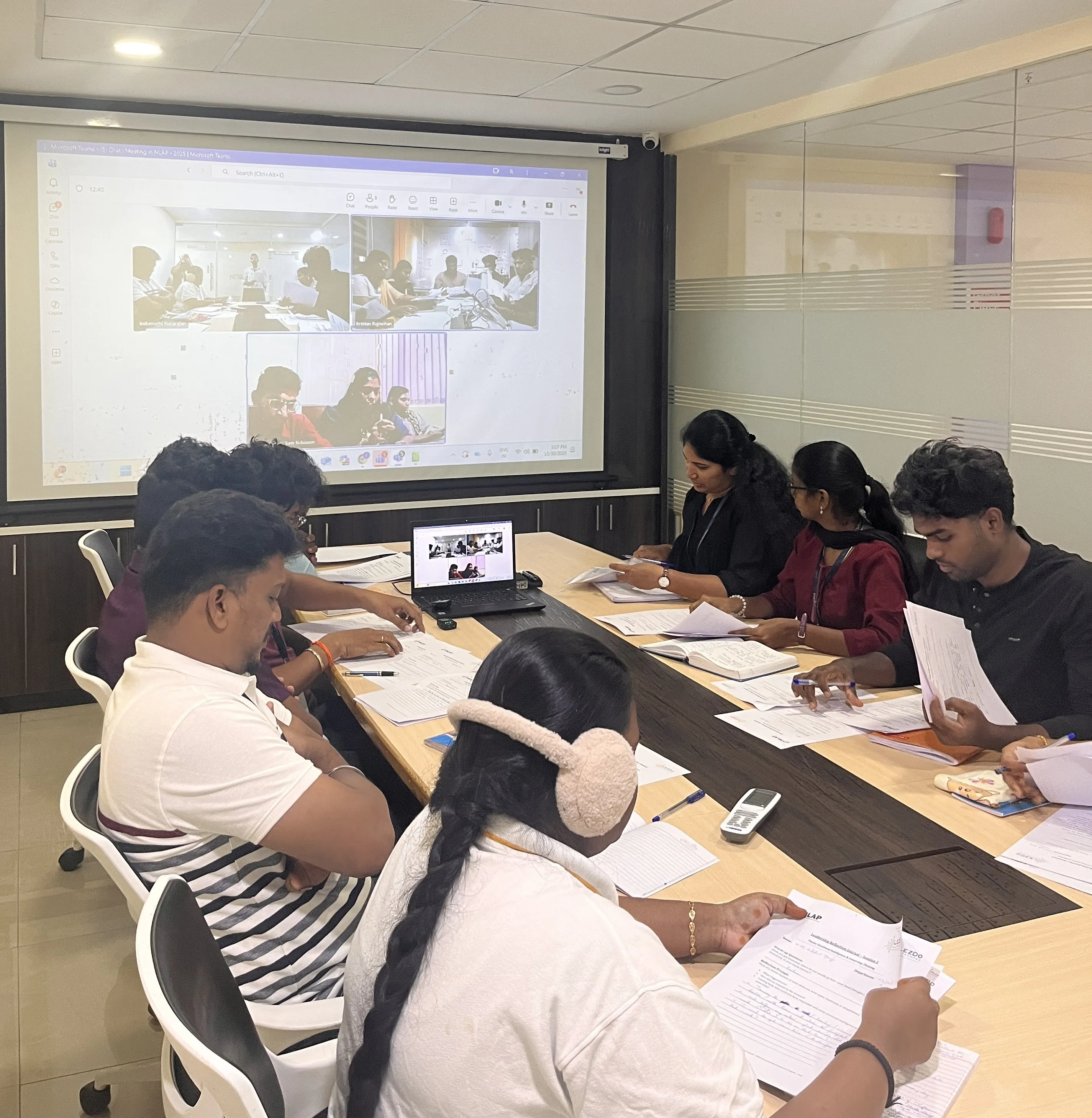 A grayscale image of a brainstorming session at a whiteboard, styled with rounded corners.