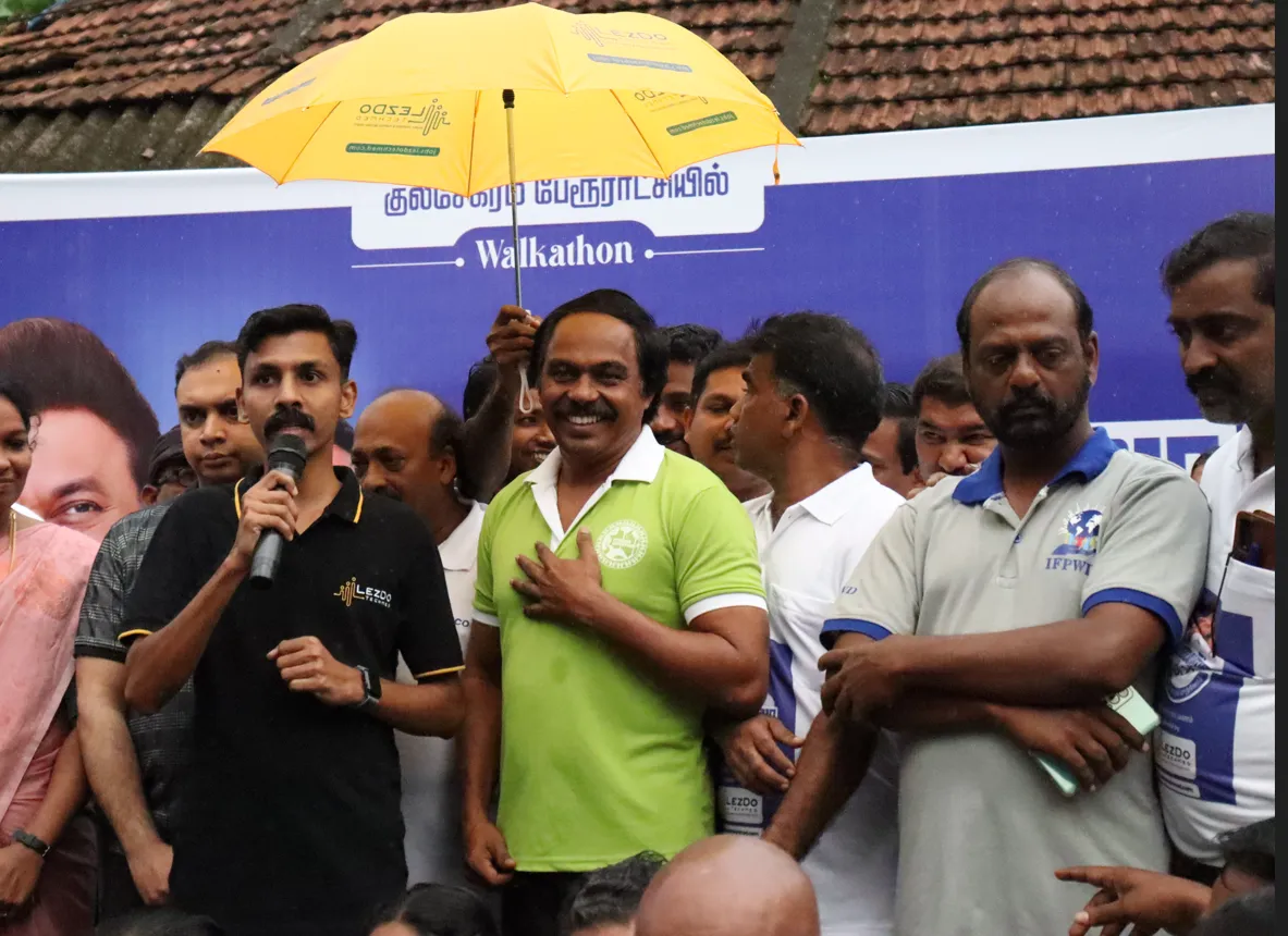 A grayscale photograph of many hands covered in paint joined together in a circle.