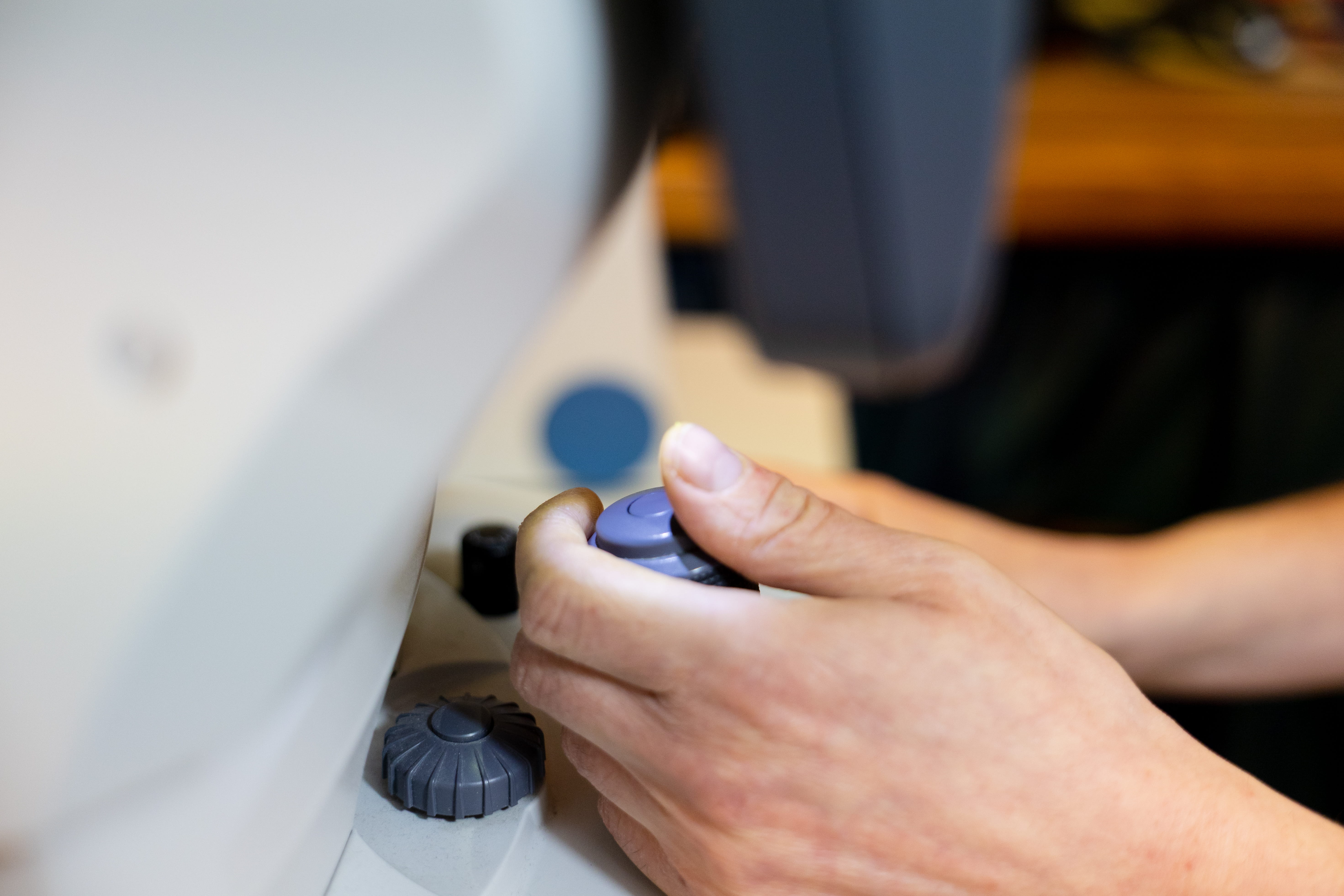 Close-up of hands adjusting focus knobs on a microscope.