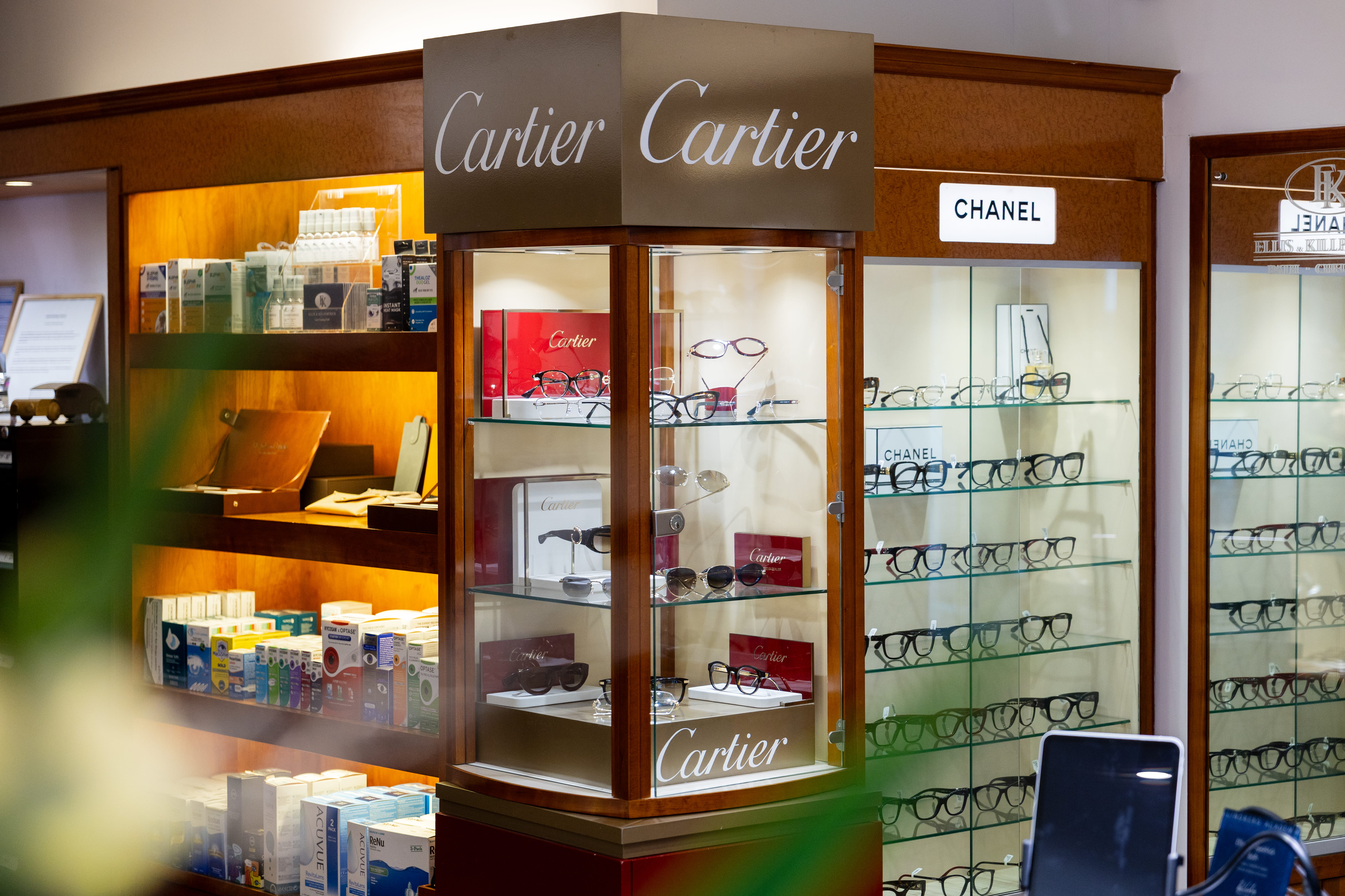 Display cases featuring Cartier and Chanel eyeglasses in a well-lit retail store.