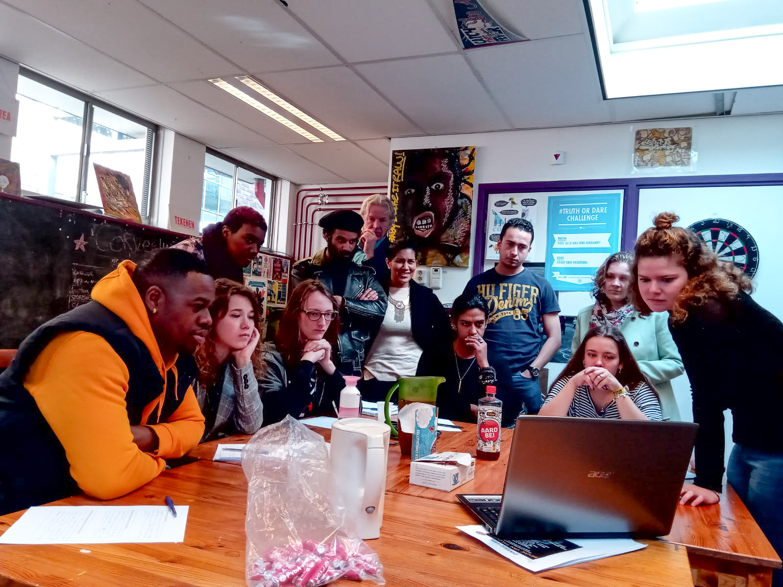 Groep met stagiaires van de HVA bij Dynamic Arts in Laren die kijken naar een presentatie op een laptop.