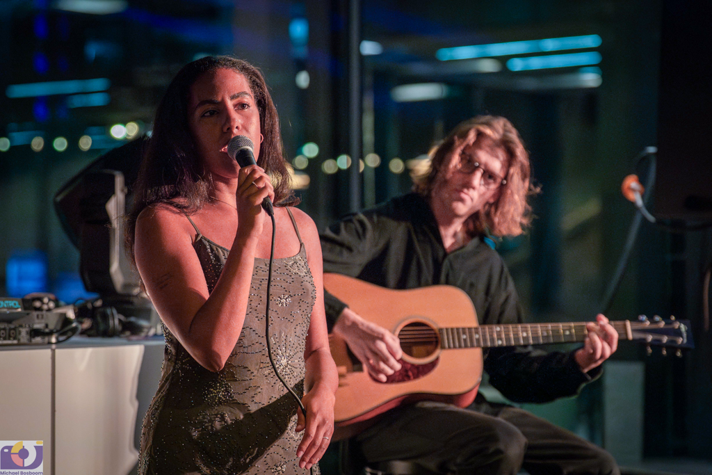 Foto van een optreden van een jonge zangeres en gitarist tijdens een activiteit van Dynamic Arts in het Singer Laren