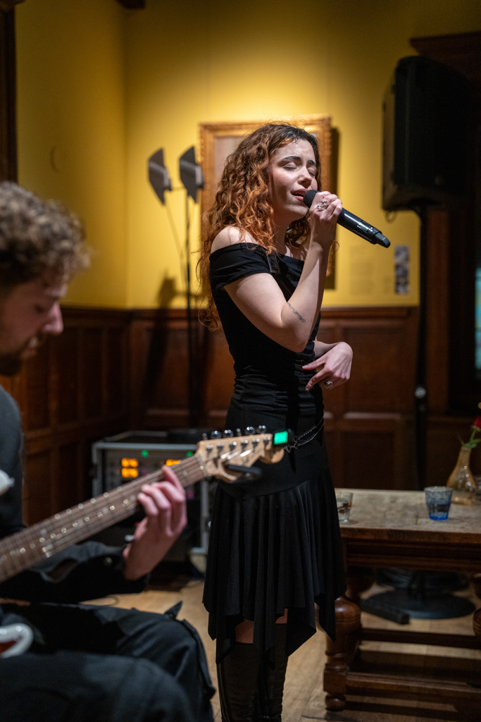 Foto van een optreden van een jonge zangeres en gitarist tijdens een activiteit van Dynamic Arts in het Singer Laren