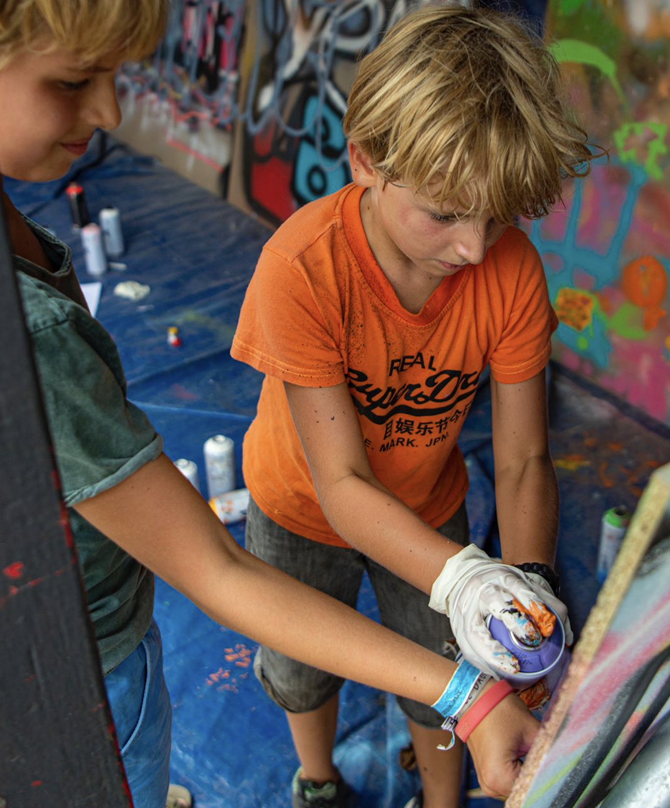 Jonge jongen graffiti aan het spuiten bij Dynamic Arts Laren.
