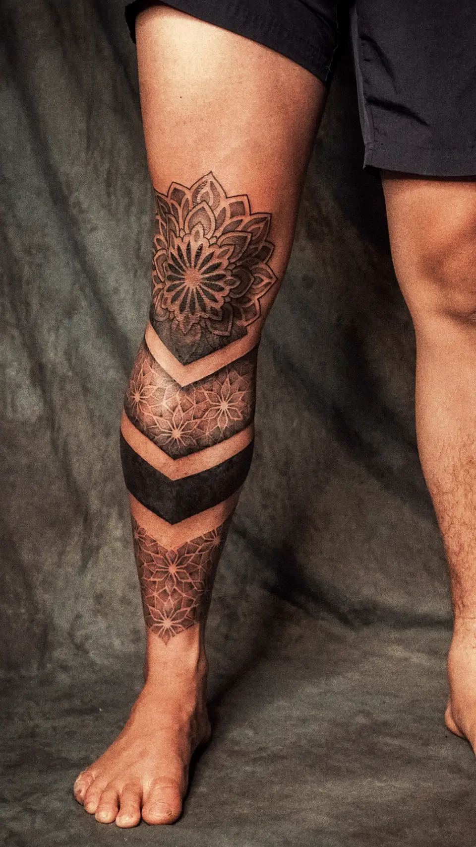 Leg tattoo featuring geometric and floral mandala patterns extending from the knee to the ankle.