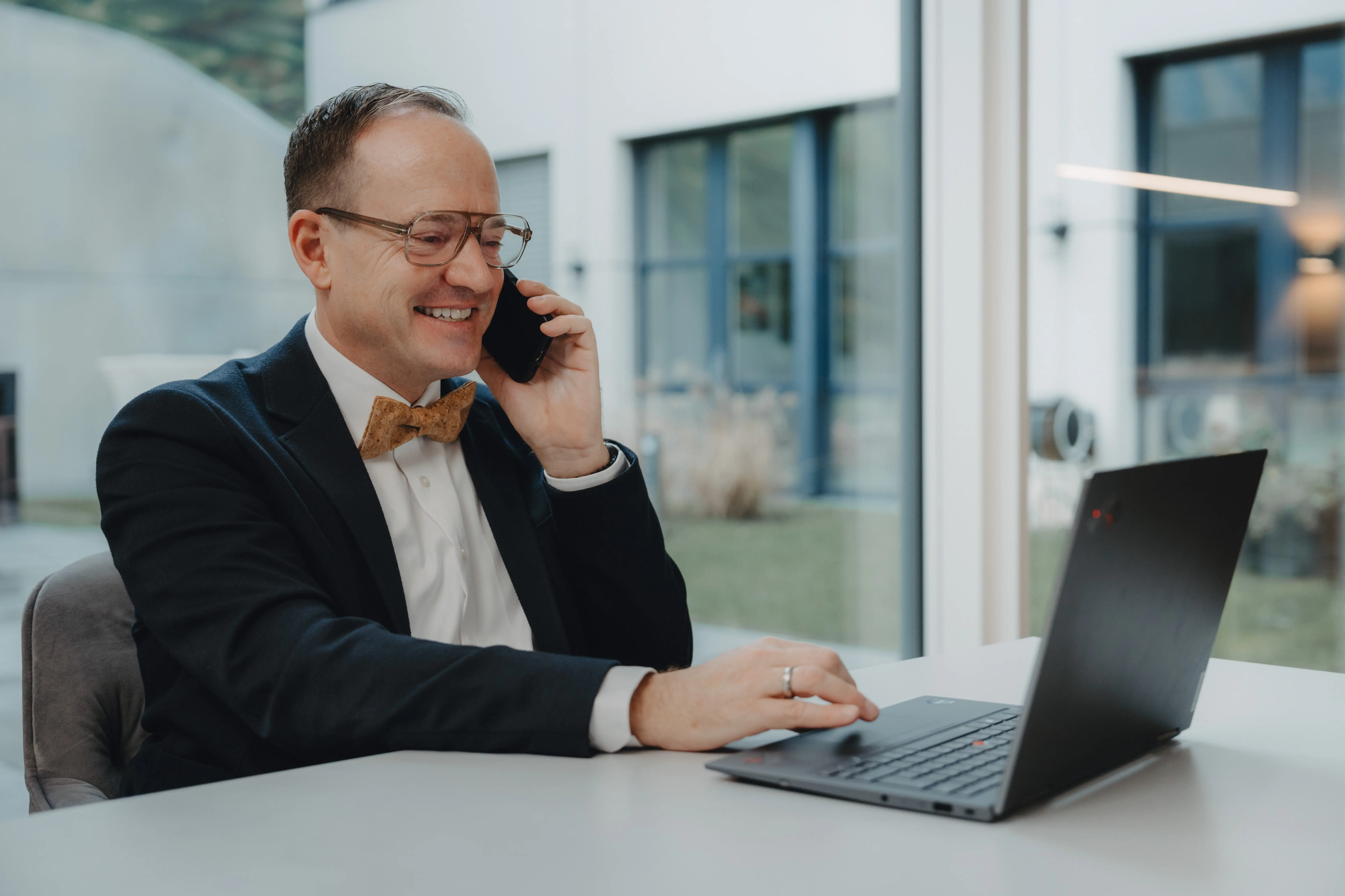 Zwei Männer mit verschränkten Armen stehen vor einer Wand, die mit US-Dollar-Scheinen bedeckt ist.