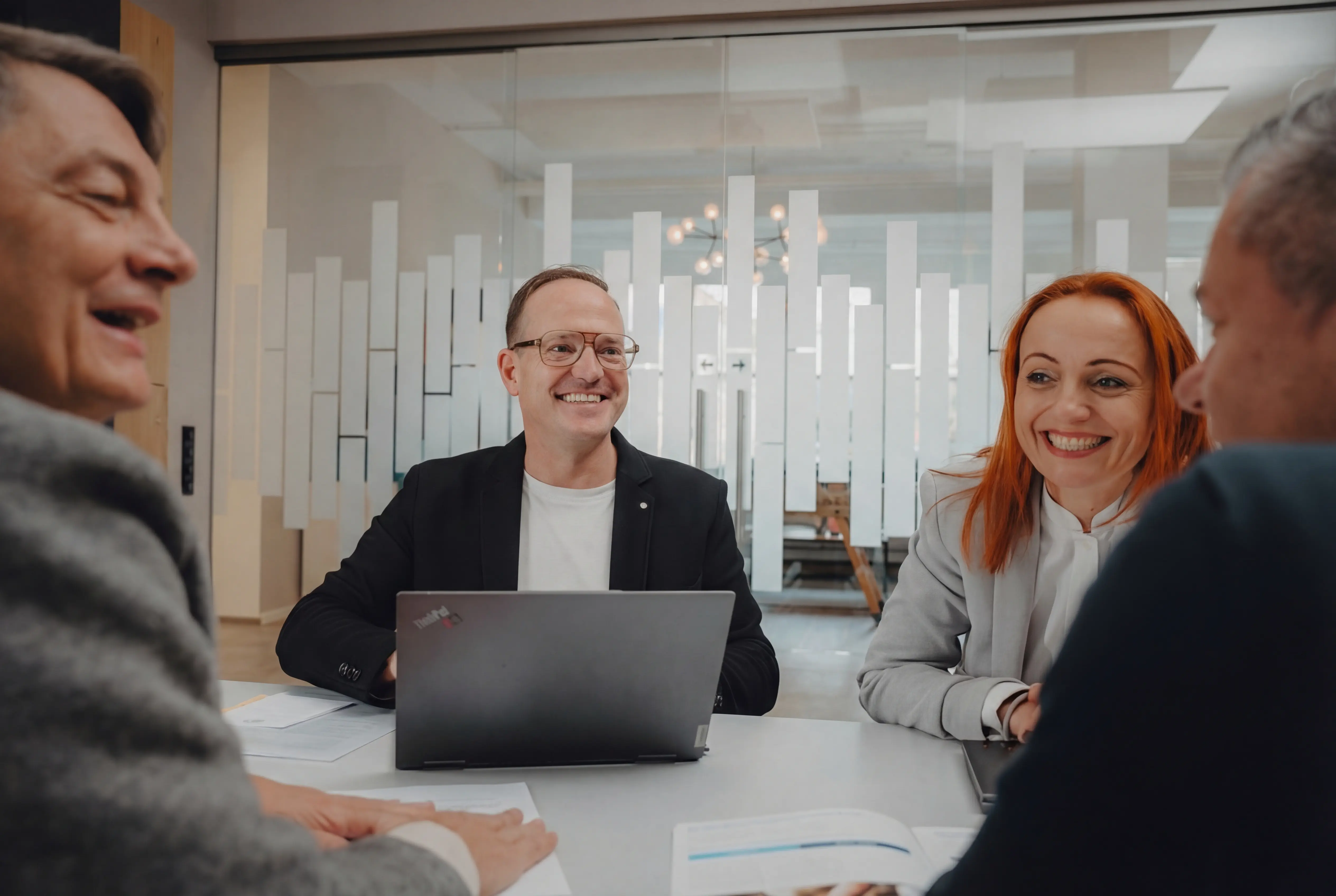 A guy smiling in the camera with a laptop infront of him