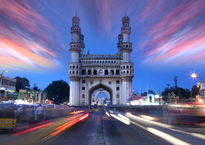 Charminar monument in Hyderabad with blurred vehicle lights and colorful twilight sky.