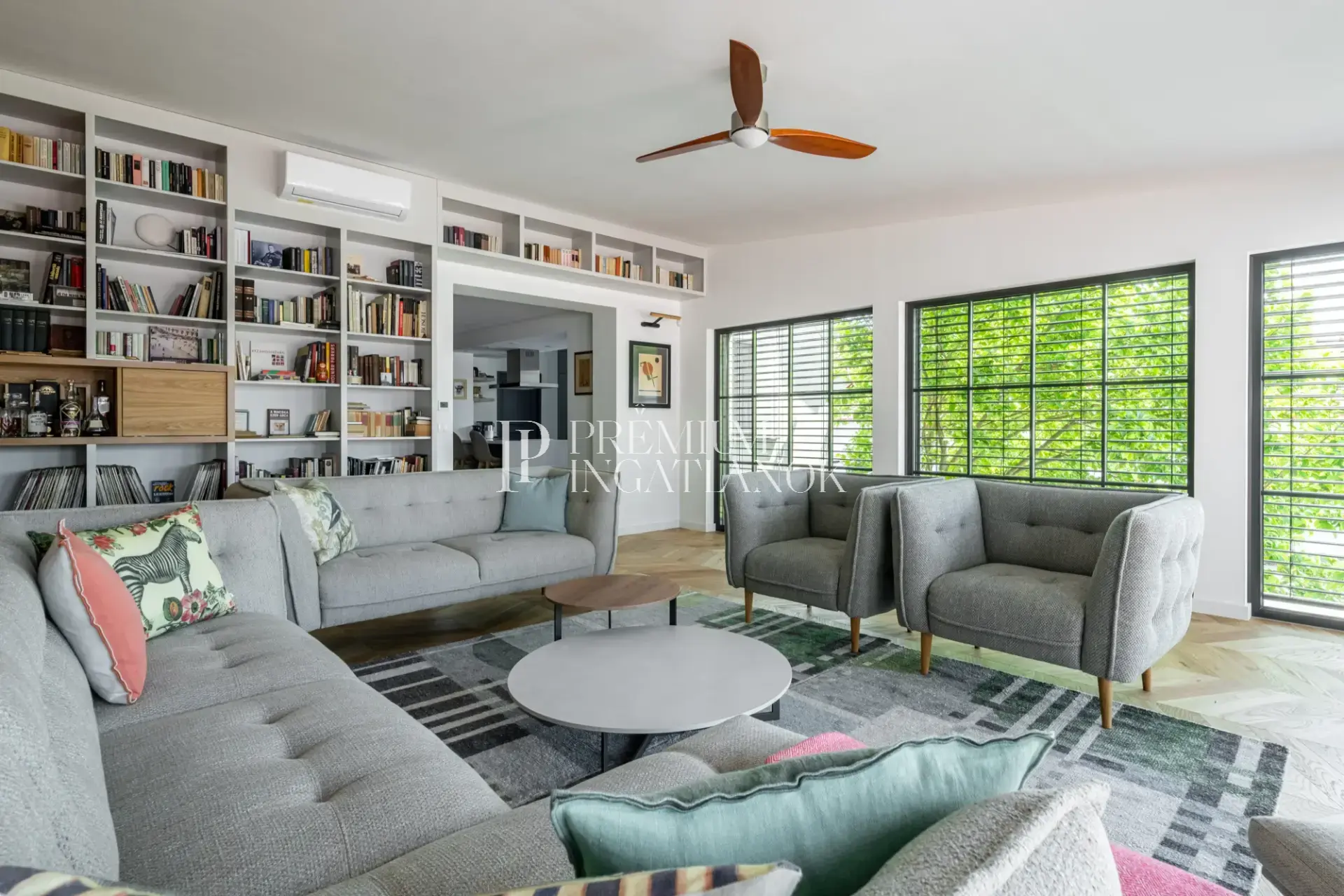 Nyitott terű nappali és étkező fehér kanapéval, kék szőnyeggel és magas minőségű Teka Chevron tölgy parkettával Száron.