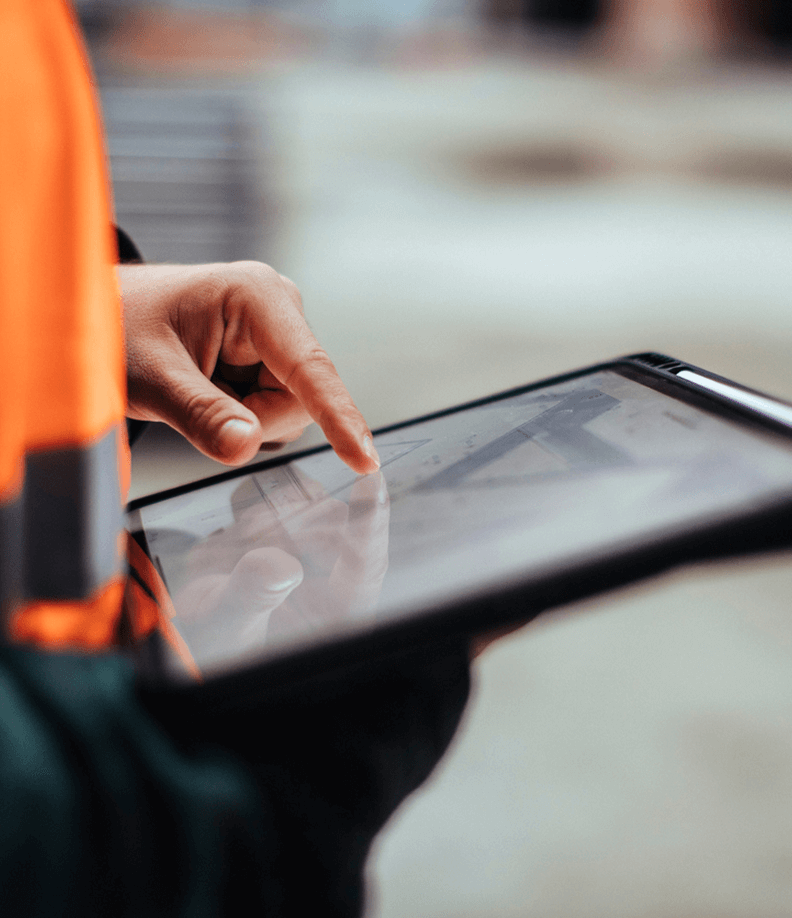 Person im Bauwesen tippt auf Tablet im Freien.