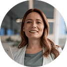 Eine lächelnde Frau in einem hellen Büro, hält ein Tablet.