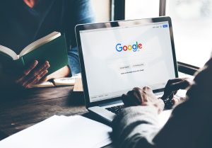 Hands typing at a laptop showing the Google search page