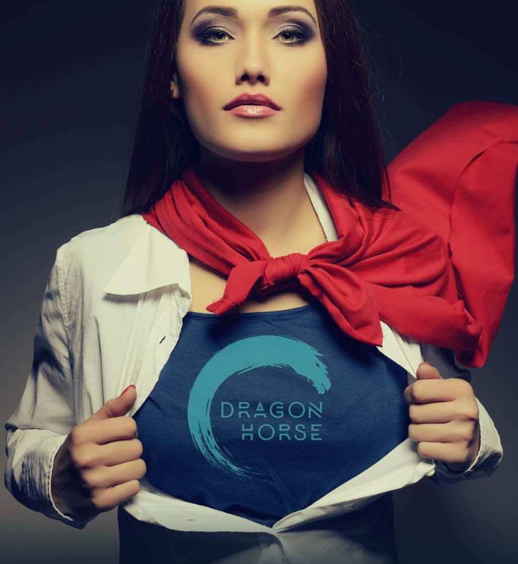 A woman in a red cape opening her shirt to reveal the Dragon Horse logo