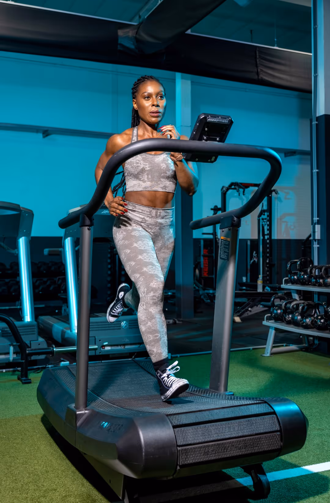 Smiling man in an orange patterned sweater sitting indoors with arms crossed.