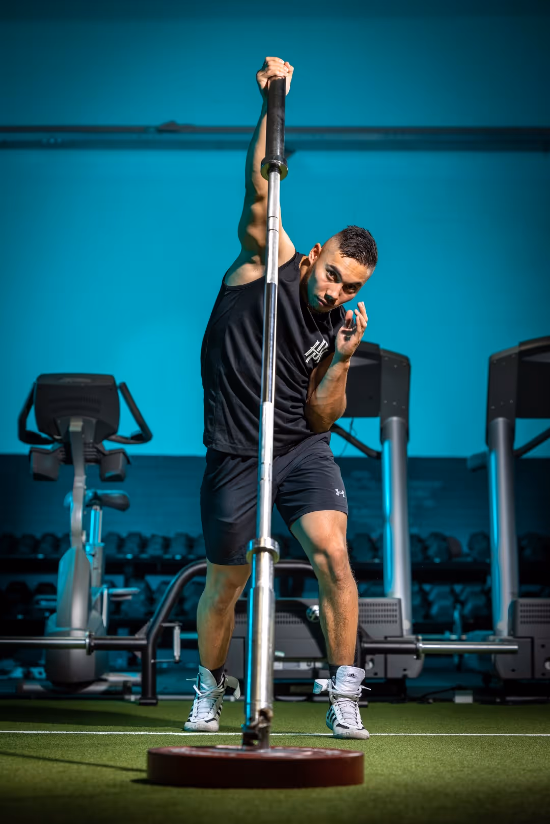 Smiling man in an orange patterned sweater sitting indoors with arms crossed.