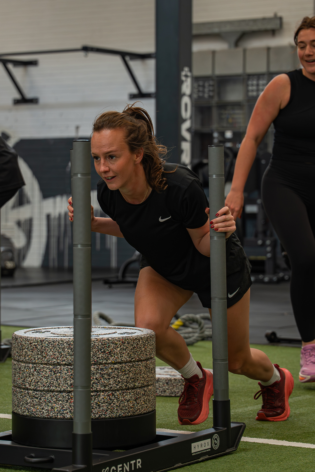 Smiling man in an orange patterned sweater sitting indoors with arms crossed.