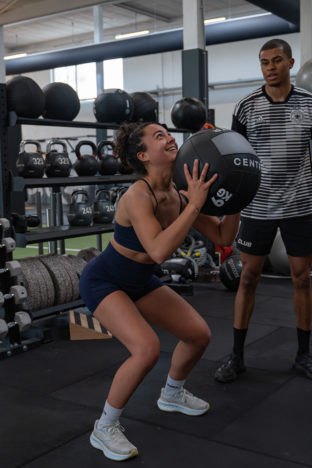 Smiling man in an orange patterned sweater sitting indoors with arms crossed.
