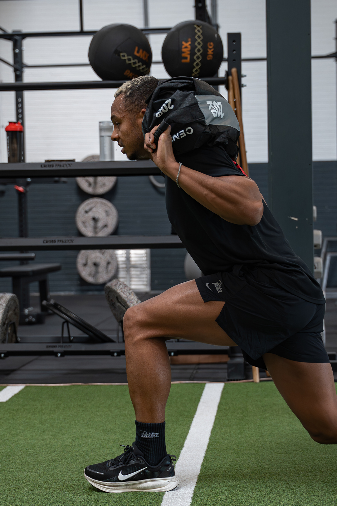 Smiling man in an orange patterned sweater sitting indoors with arms crossed.