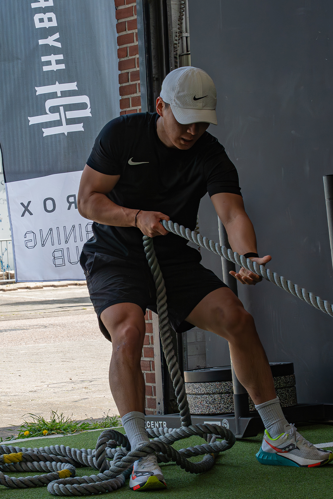 Smiling man in an orange patterned sweater sitting indoors with arms crossed.