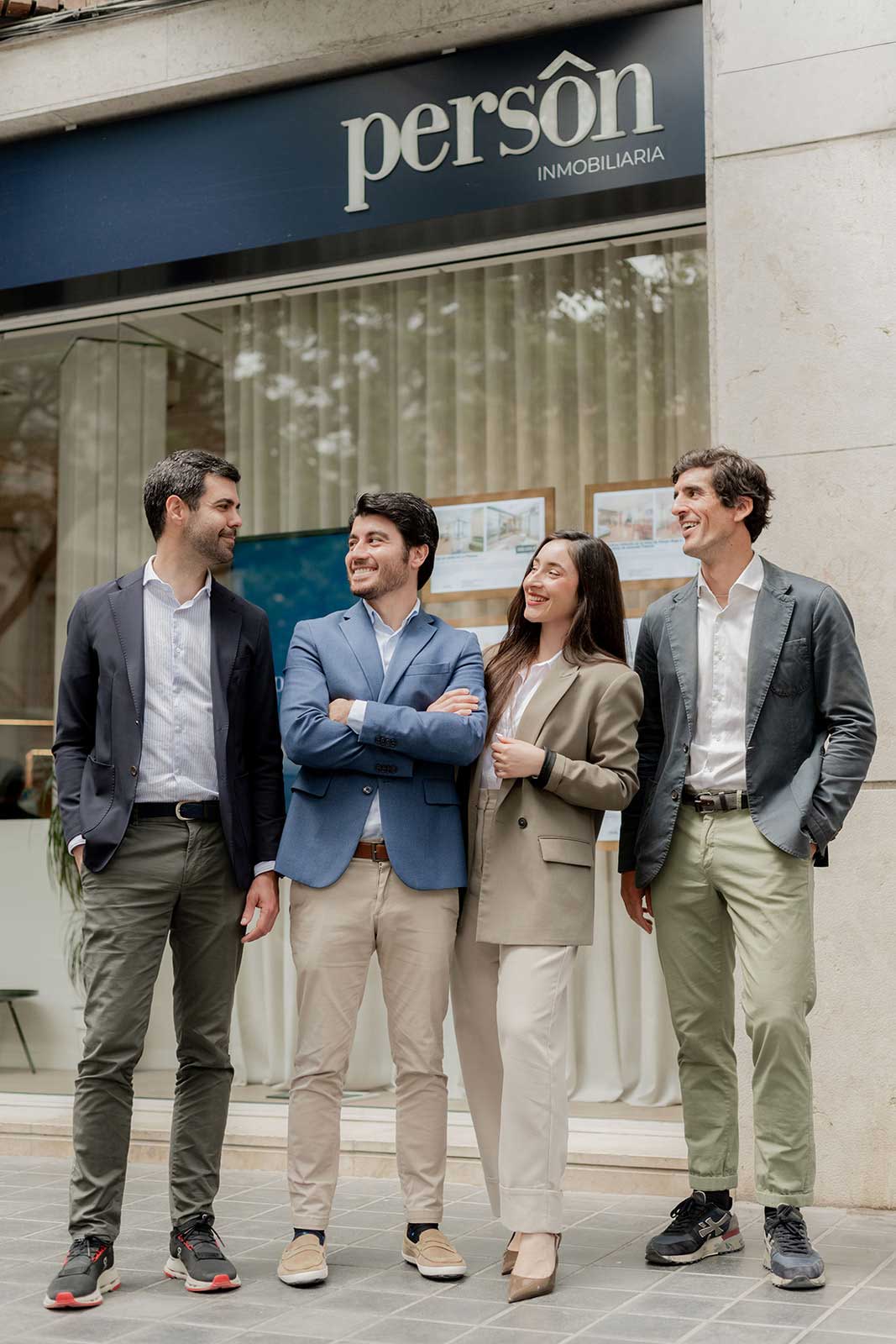 Cuatro agentes inmobiliarios sonrientes frente a la oficina de Person Inmobiliaria.