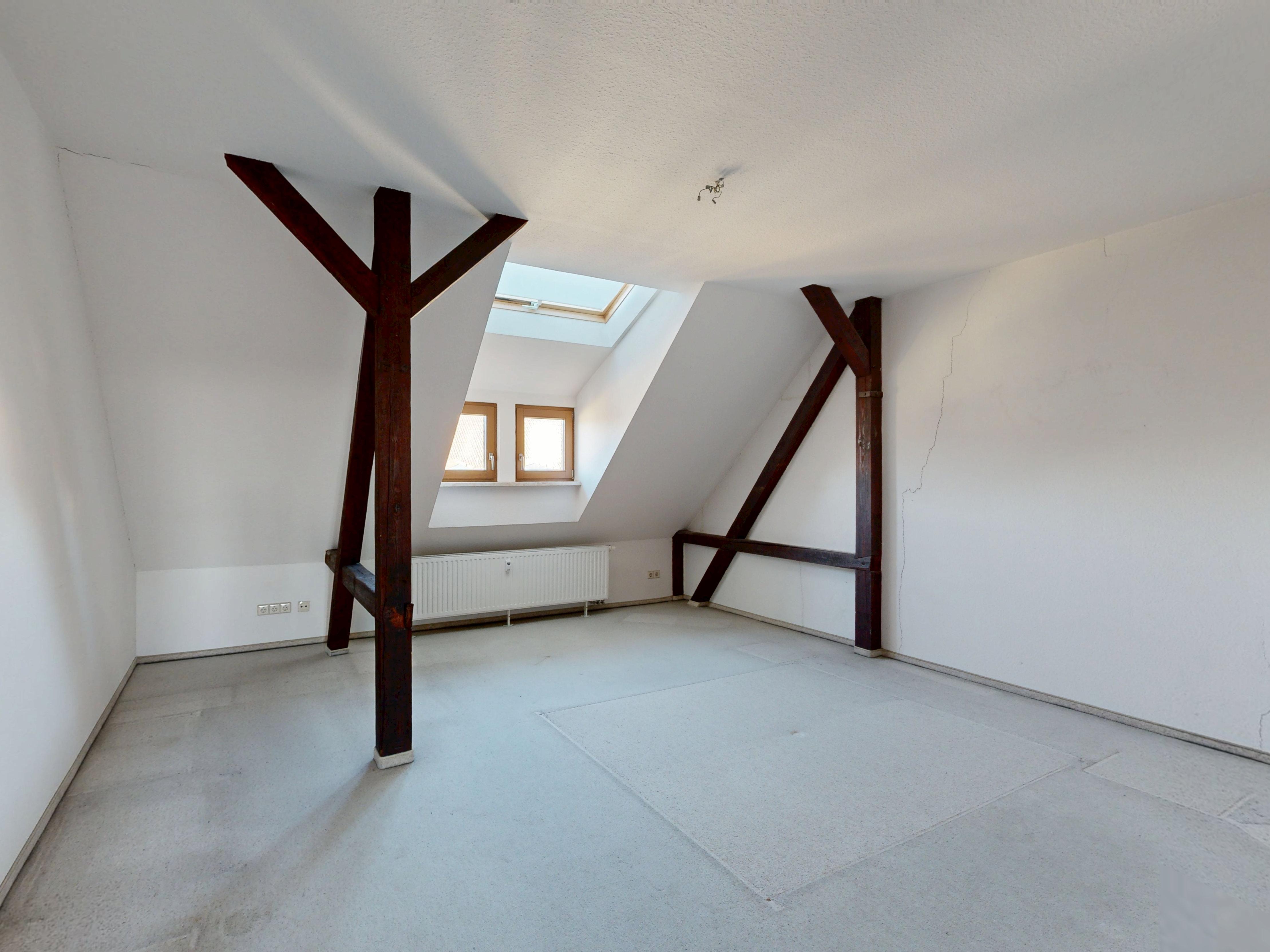 Dachgeschosszimmer vor der Sanierung mit Teppichboden und sichtbarem Gebälk
