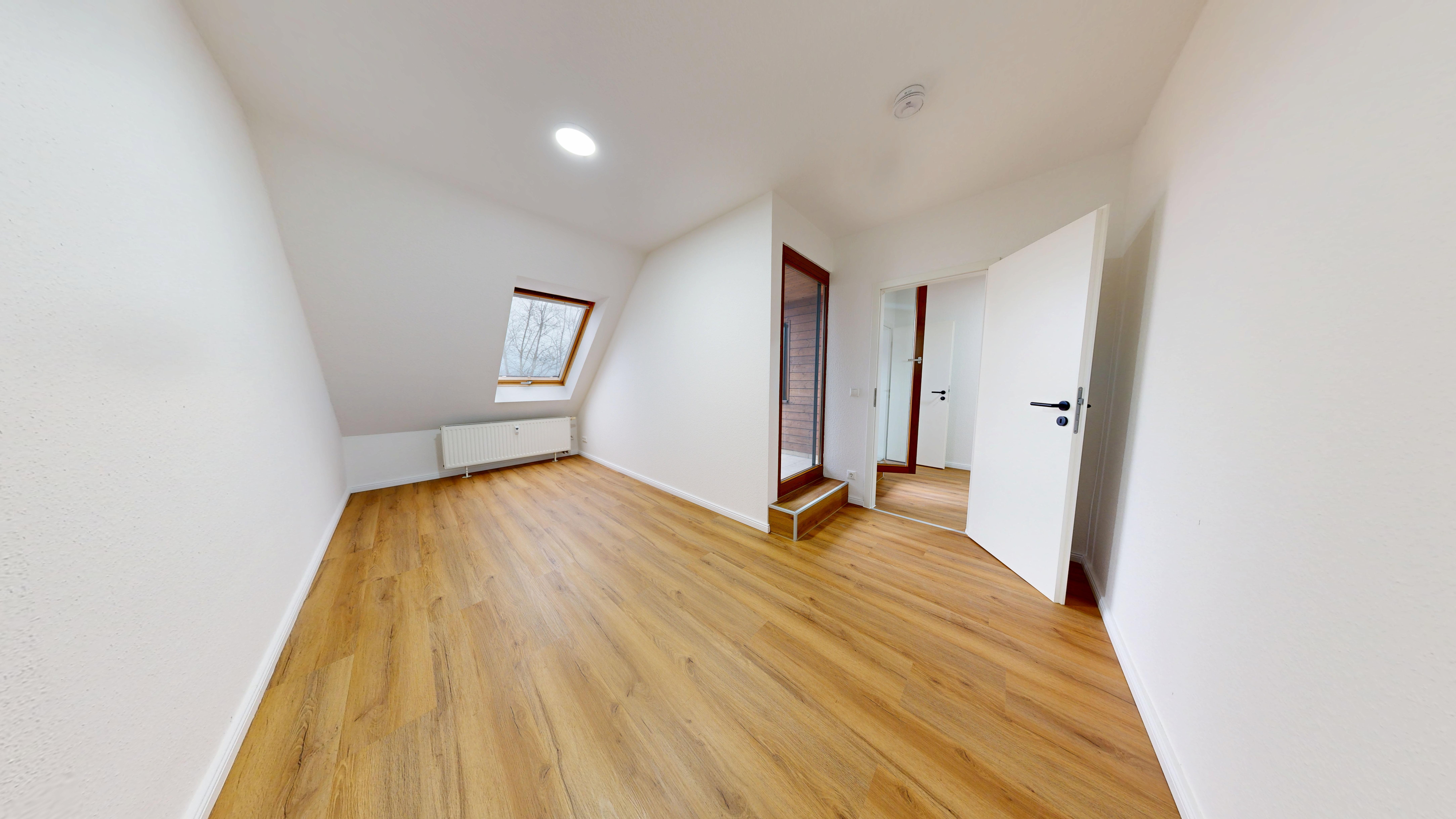 Zimmer mit Balkontür nach der Sanierung, neuer Boden und neue Tür