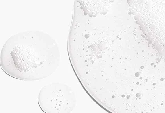 Gouttes claires et mousseuses de sérum ou gel cosmétique sur fond blanc.