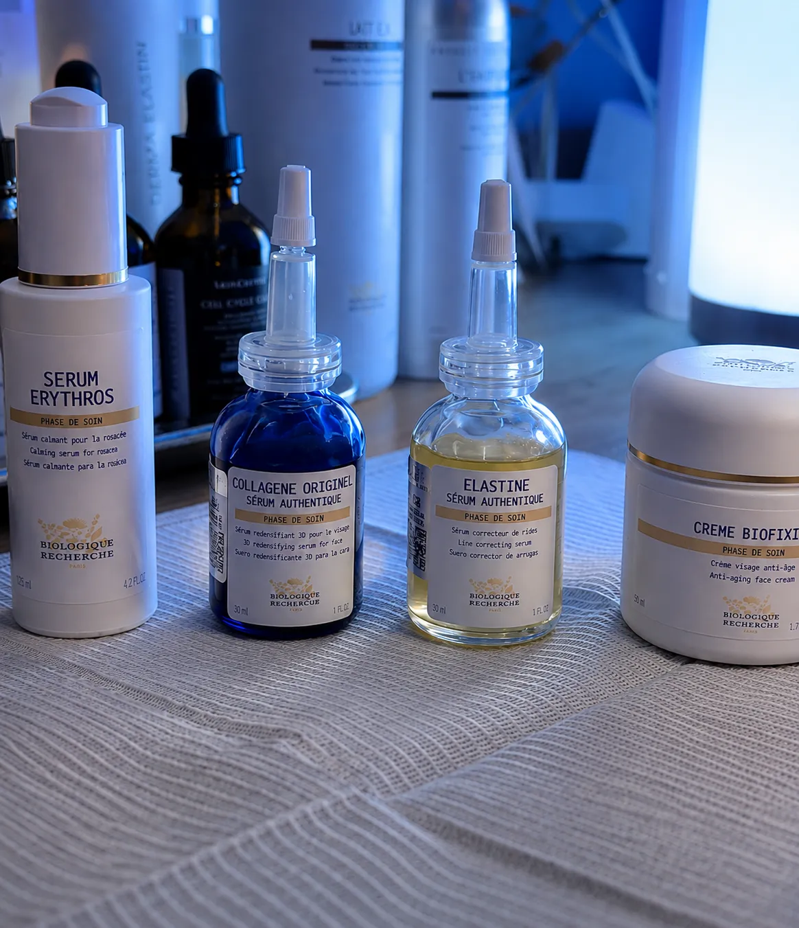 Quatre produits de soins de la peau Biologique Recherche alignés : sérum calmant Erythros, sérum authentique Collagène Originel, sérum authentique Elastine et crème biofixine anti-âge.