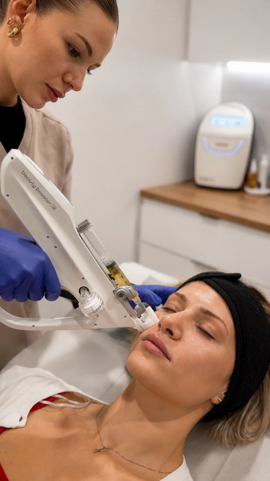 Clinicienne effectuant un traitement du visage au dispositif Beauty Booster sur une patiente allongée.
