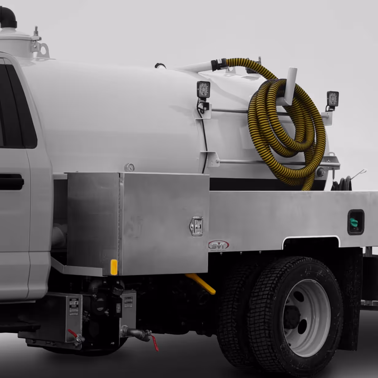 Close-up of white tanker truck with yellow coiled hose and metal storage box on its side.