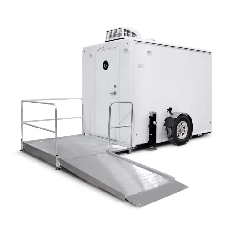 White portable ADA-compliant trailer with a wheelchair ramp and a door marked with a disability sign.