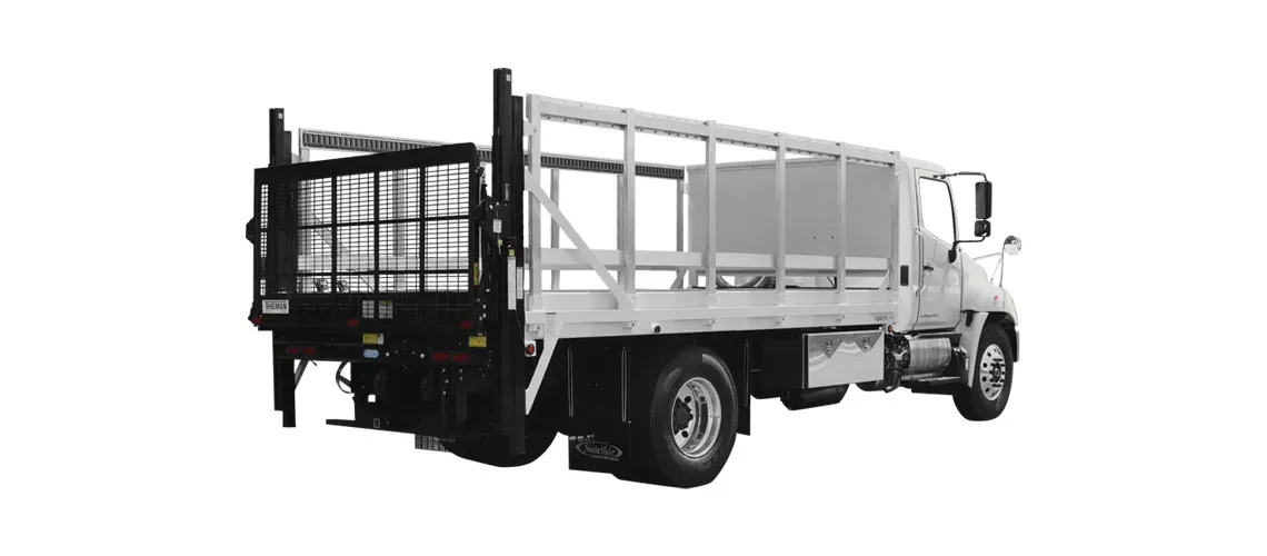 White flatbed truck with metal side rails and black lift gate at the rear.